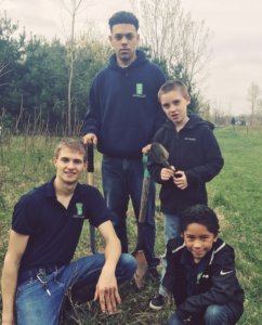 Four WMAES students standing in the yard with yard tools.
