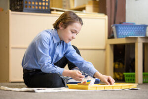 Young student uses Montessori materials in the classroom by himself.