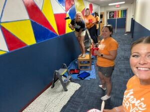 Photograph of the Choice Schools Associates team painting a mural at Bradford Academy for Choice Serves